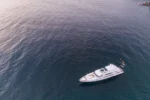 Aerial view of a luxury motor yacht anchored near a rocky coastline