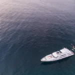 Aerial view of a luxury motor yacht anchored near a rocky coastline