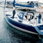 The stern of a sailing yacht named Our Dream, with her home port of Middelfart lettered beneath the name, moored among other craft in a Danish marina