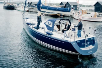 The stern of a sailing yacht named Our Dream, with her home port of Middelfart lettered beneath the name, moored among other craft in a Danish marina