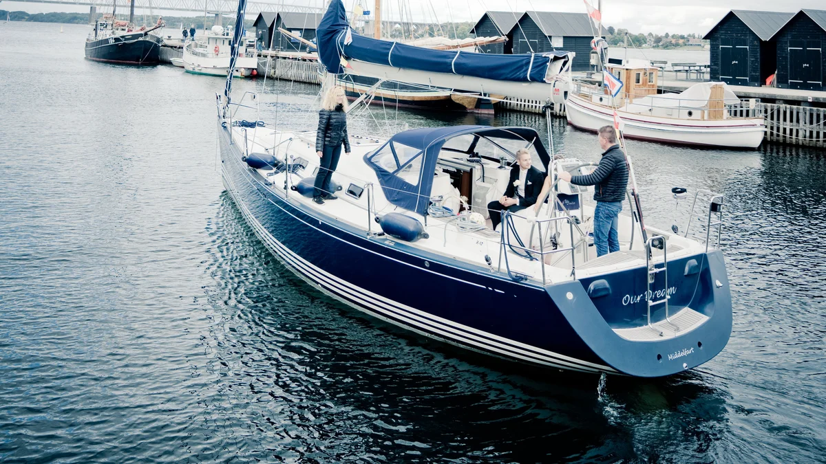 The stern of a sailing yacht named Our Dream, with her home port of Middelfart lettered beneath the name, moored among other craft in a Danish marina