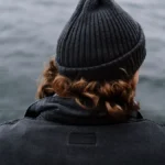 A yacht crew member looks out over the sea from the deck of a yacht, a quiet moment reflecting on life onboard.
