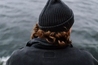 A yacht crew member looks out over the sea from the deck of a yacht, a quiet moment reflecting on life onboard.