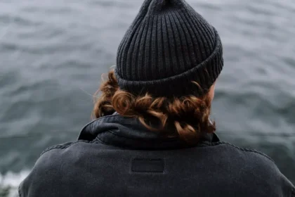 A yacht crew member looks out over the sea from the deck of a yacht, a quiet moment reflecting on life onboard.