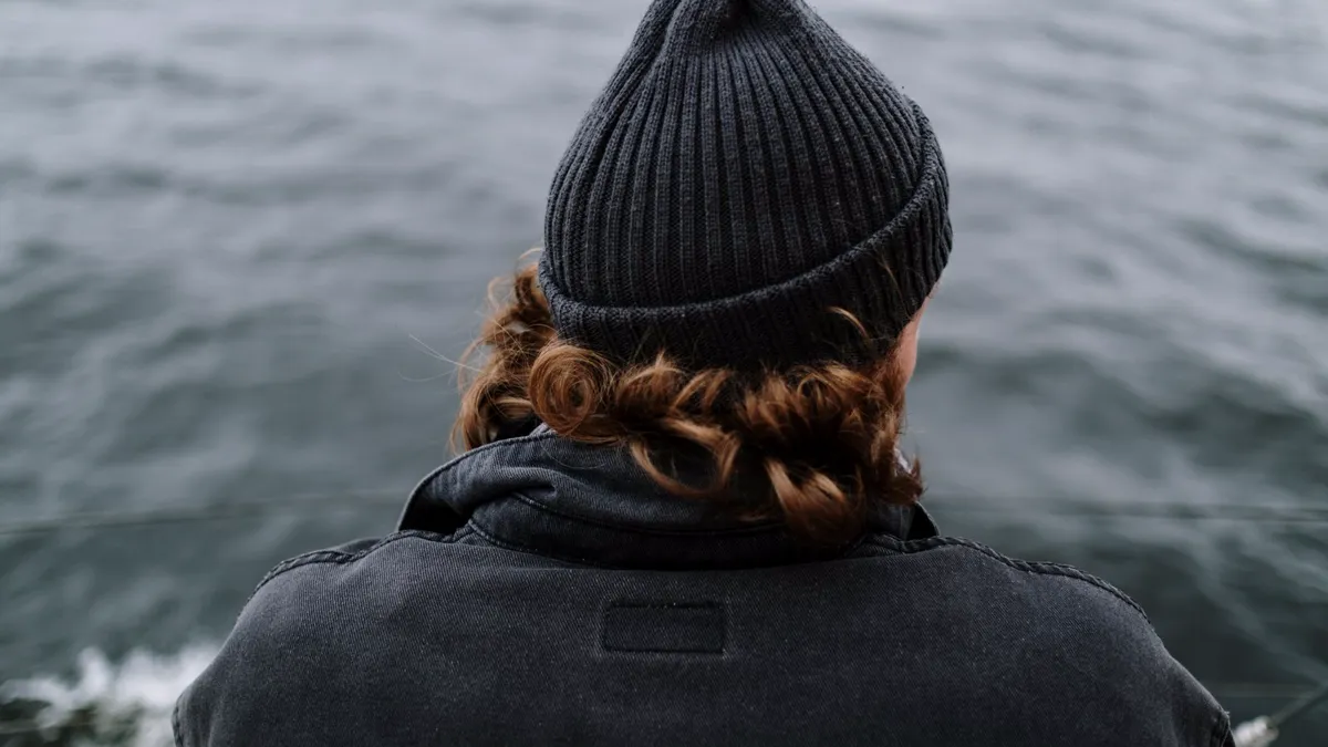 A yacht crew member looks out over the sea from the deck of a yacht, a quiet moment reflecting on life onboard.
